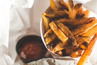 Golden crispy fries spilling out of a red carton with a side of ketchup.