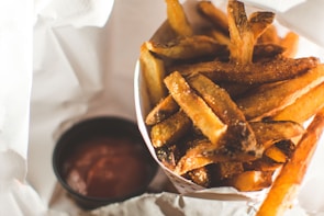 Golden crispy fries served in a red carton with a side of ketchup.