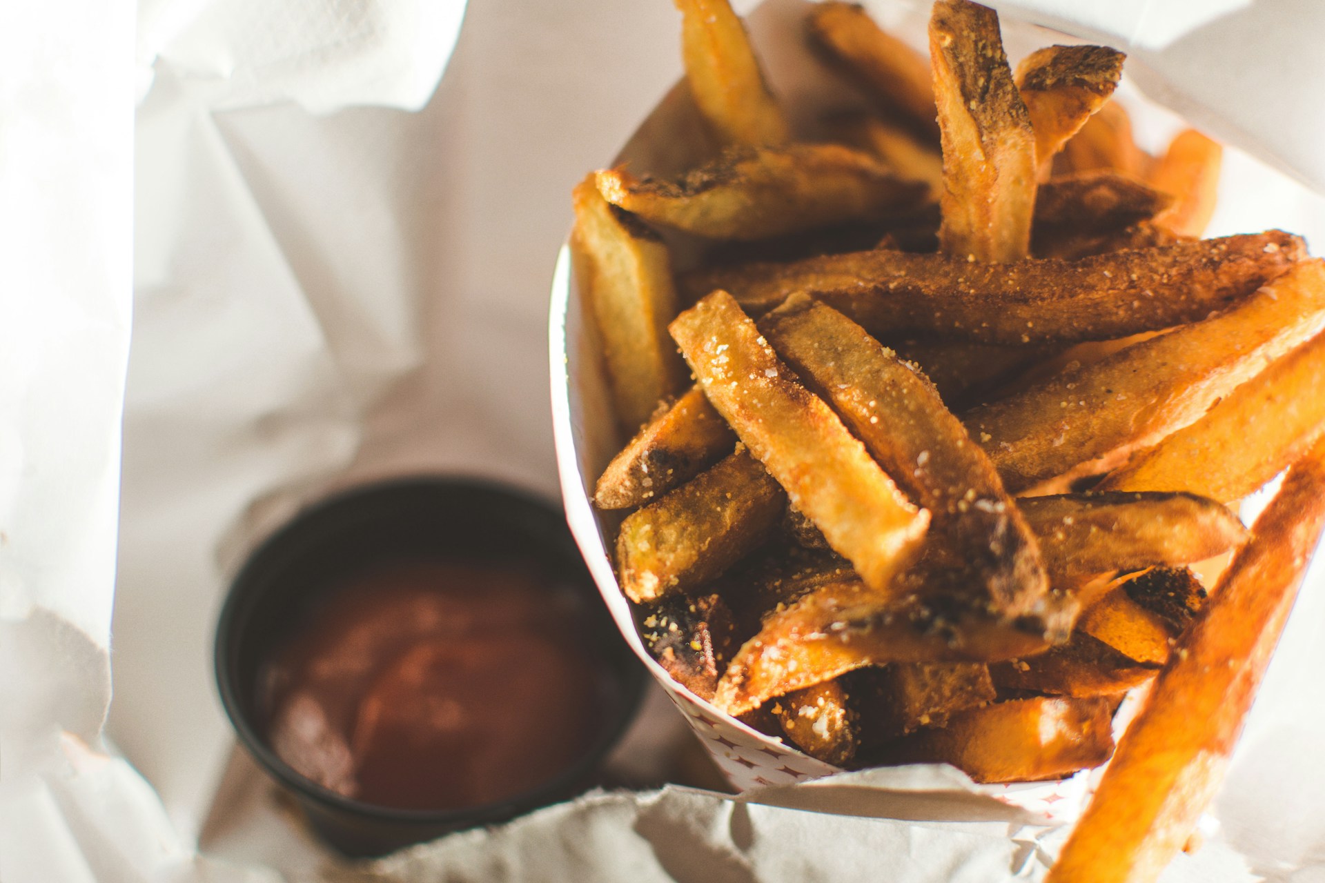 Close-up of crispy golden fries served in a dino-shaped basket with a side of ketchup.