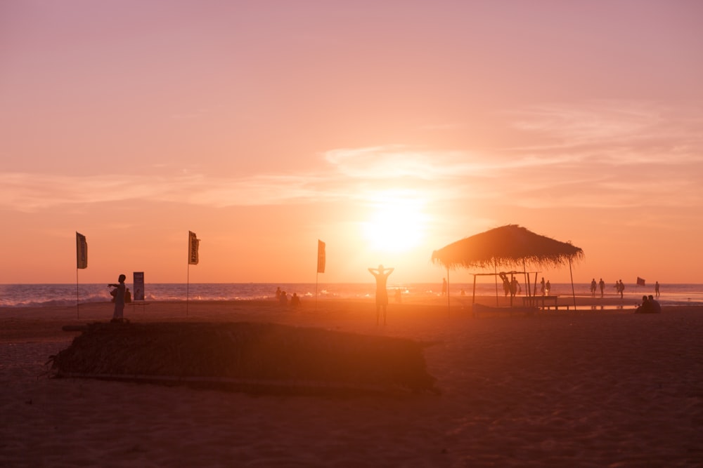 Cabana de praia de silhueta perto da costa durante o pôr do sol