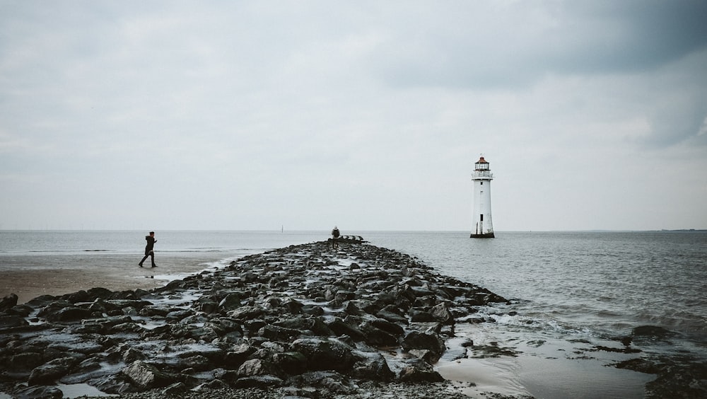 grayscale photography of lighthouse on sea