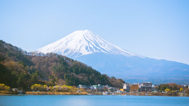 Snow-capped Mount Fuji towering over a serene lake with autumn foliage.