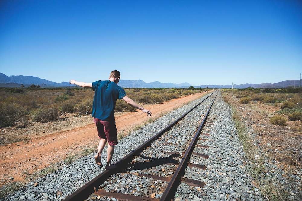 person walking on brown steel train rail outdoor during daytime