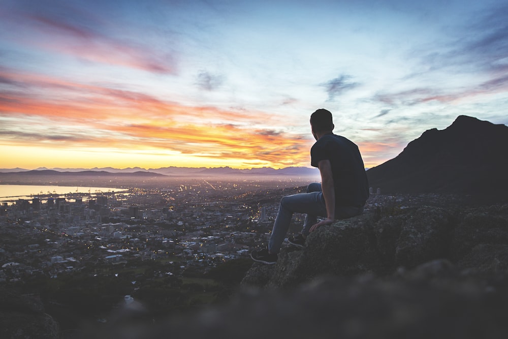 man sitting on rock in front of sea