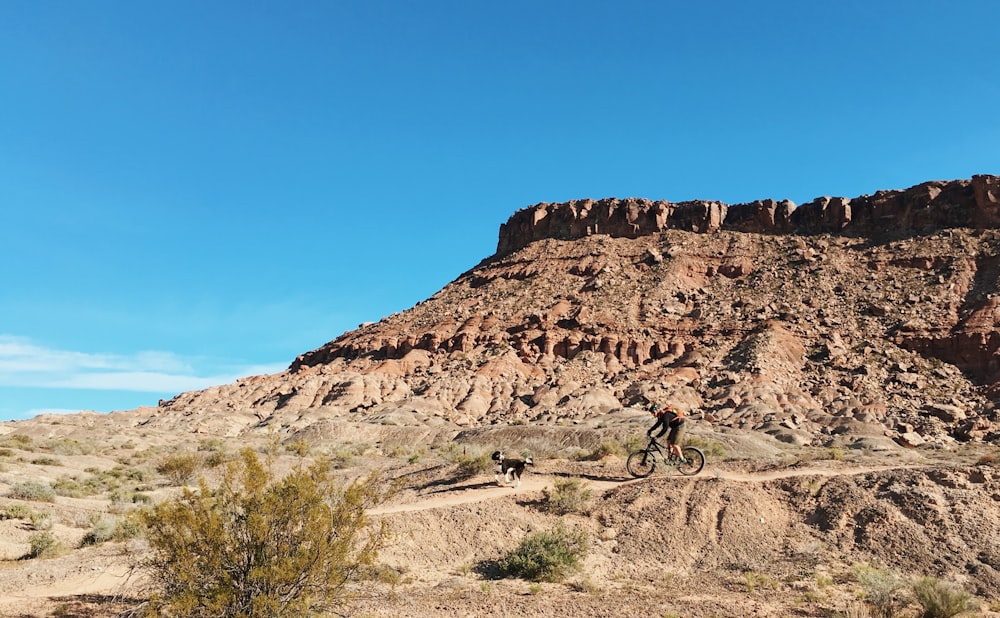 person riding bicycle near brown rock formation during daytime