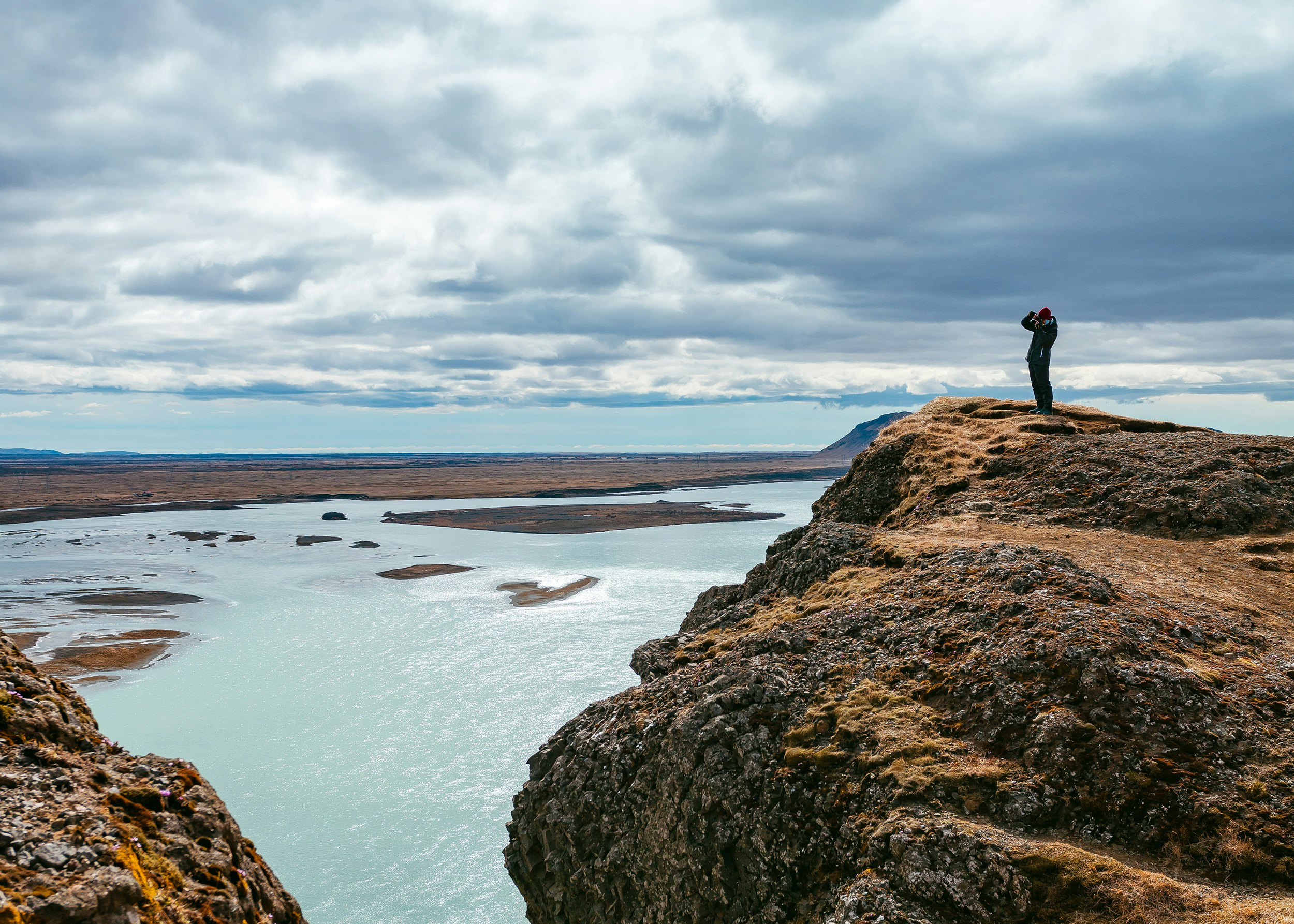 person standing on rock formation near body of water during daytime