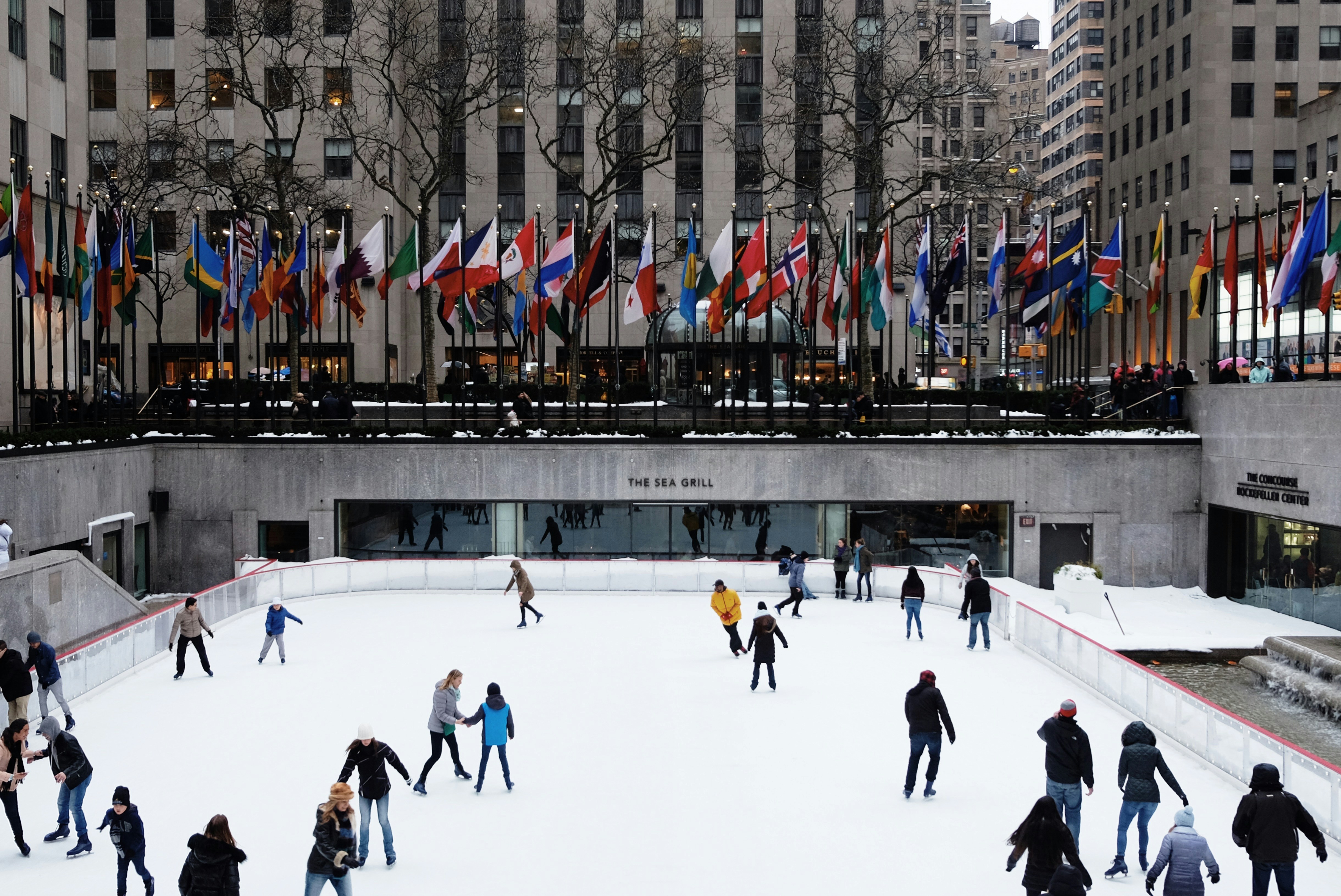people ice skating on field surrounded by high-rise buildings