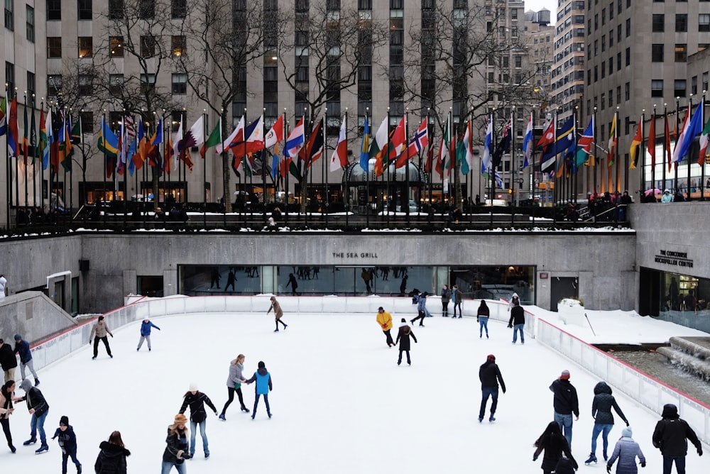 people ice skating on field surrounded by high-rise buildings