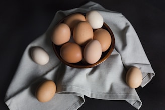 beige and white eggs on brown wooden bowl
