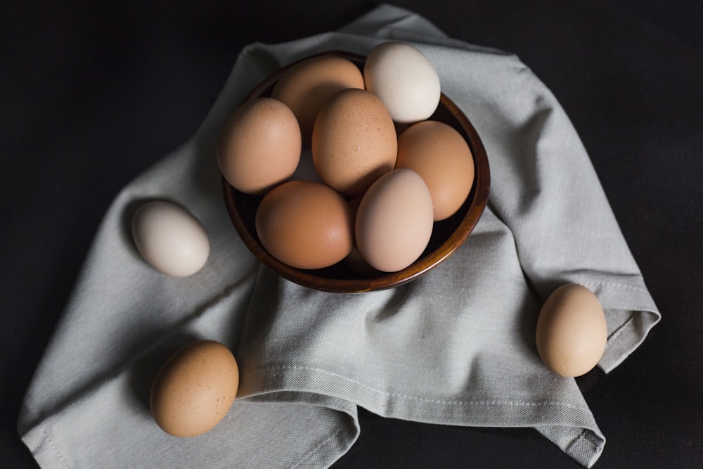 huevos beige y blancos en un cuenco de madera marrón