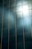 Tall glass windows reflect sunlight, creating a bright and glaring effect across the surface. The light bounces off the glass, casting beams and a soft glare in the surrounding areas.