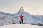 person in red hoodie standing on snowy mountain during daytime