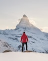 person in red hoodie standing on snowy mountain during daytime