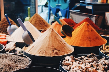 Piles of colorful spices and grains spread on market stalls.