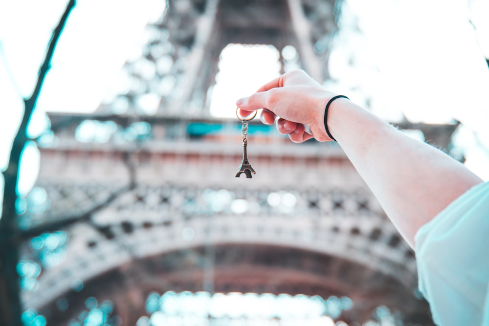 personne tenant un porte-clés de la Tour Eiffel