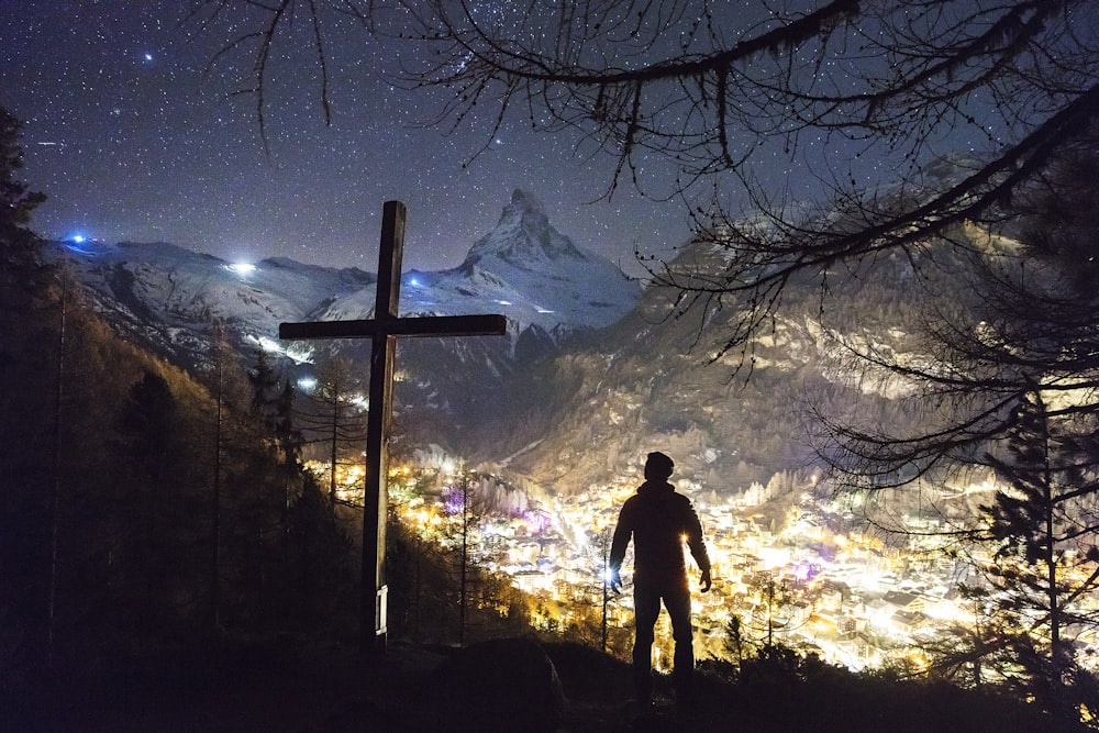 Hombre parado cerca de la cruz durante la noche