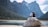 a couple sits on a rock looking out over a lake