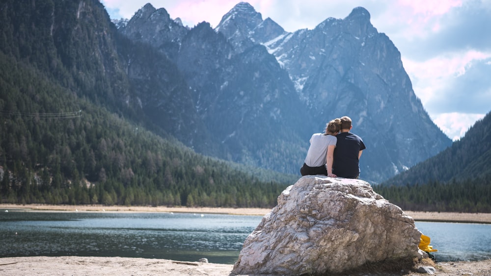 Um casal senta-se numa rocha com vista para um lago