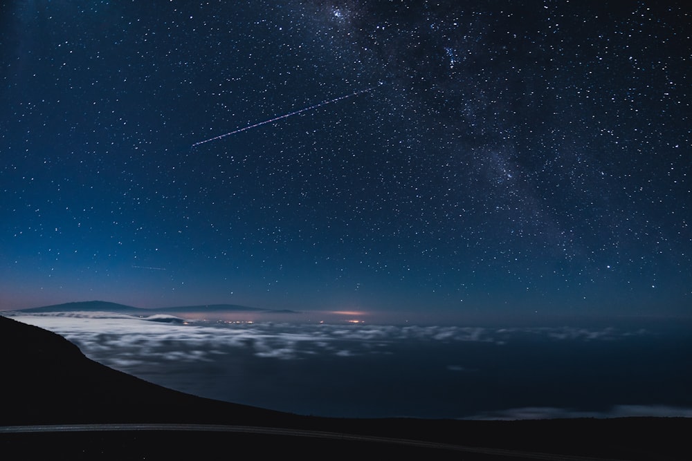 blue and black sky with stars and falling star at nighttime