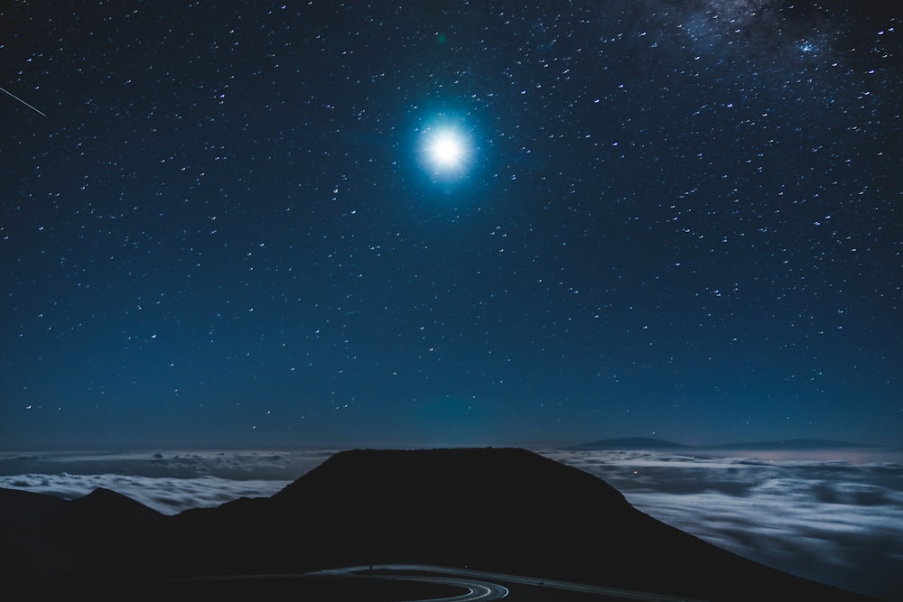 silhouette photo of body of water under blue sky at night