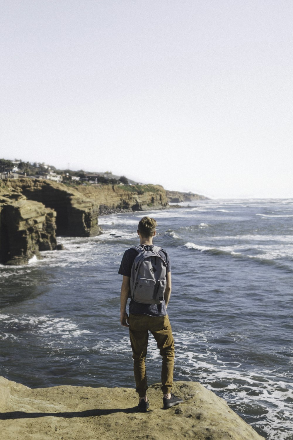 uomo in piedi sulla scogliera che guarda lo specchio d'acqua