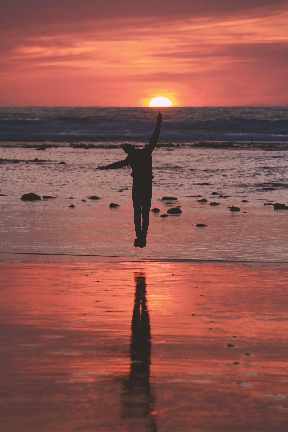 donna in vestito nero in piedi sulla spiaggia durante il tramonto