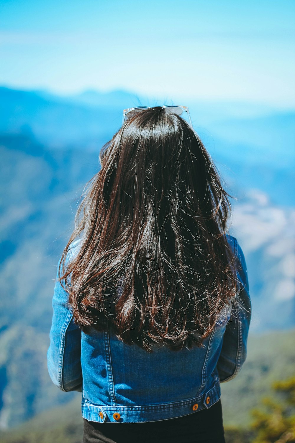 Donna che indossa una giacca di jeans blu in piedi vicino alla montagna