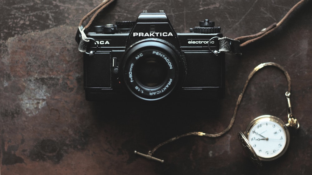 black Praktica camera and gold-colored pocket watch