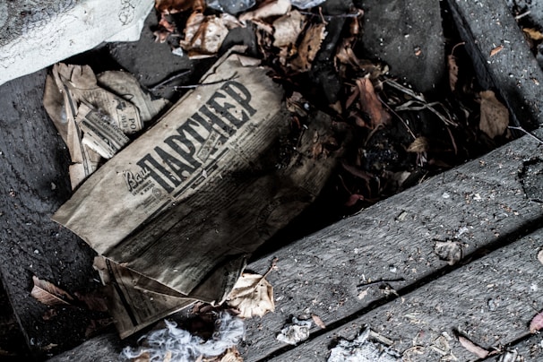 An old, weathered letter partially hidden under a cracked wooden floorboard, hinting at a family secret.