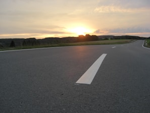 A freshly paved highway stretching through a scenic countryside at sunset