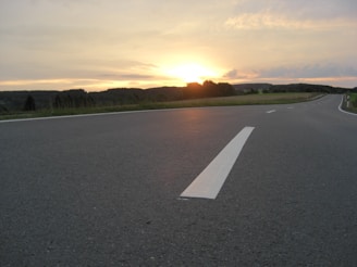 A freshly paved highway stretching through a scenic countryside at sunset