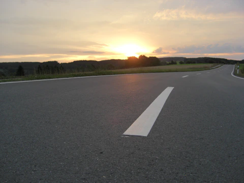 A freshly paved highway stretching through a scenic landscape at sunset.