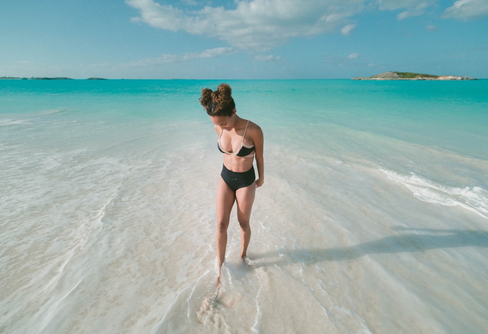 donna che indossa costume da bagno bikini mentre si trova sulla spiaggia in riva al mare durante il giorno