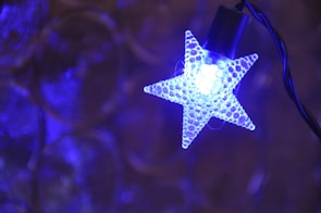 A custom blue neon light shaped like a star hanging in a cozy room.