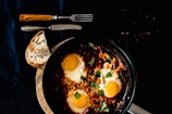 A skillet with sizzling scrambled eggs and chopped herbs.
