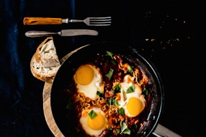 A skillet with sizzling scrambled eggs and chopped herbs.