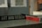 A close-up view of a table displaying a book titled 'Materials for Design' by Chris Lefteri. A black pencil rests on top of the book. In the foreground, there is a sign with the words 'Art and Design'. The background appears to be an indoor setting, slightly out of focus, with cool, muted lighting.