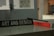 A close-up view of a table displaying a book titled 'Materials for Design' by Chris Lefteri. A black pencil rests on top of the book. In the foreground, there is a sign with the words 'Art and Design'. The background appears to be an indoor setting, slightly out of focus, with cool, muted lighting.