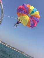 A person parasailing over the ocean with a colorful parachute.