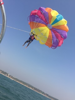 A person parasailing over the ocean with a colorful parachute.