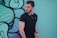 man in black polo shirt standing beside wall