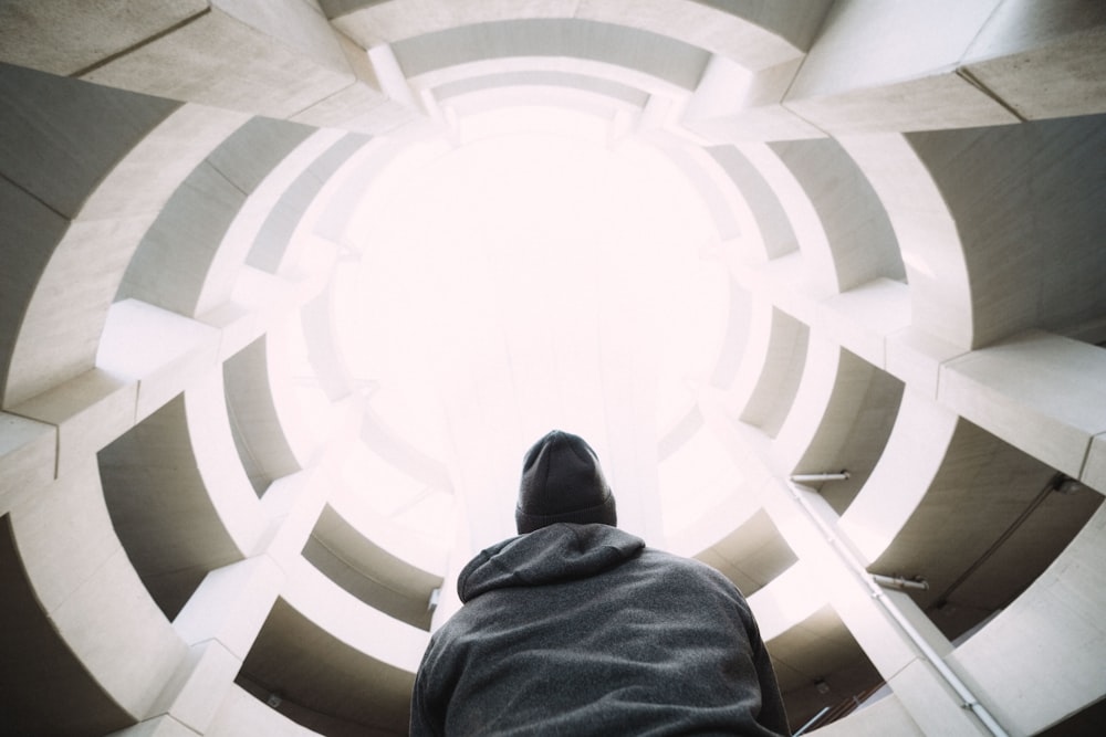 Photographie d’une personne portant une veste grise à capuchon à l’intérieur d’un bâtiment pendant la journée