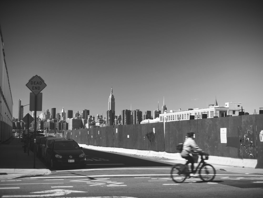 grayscale photo of person riding bicycle on road