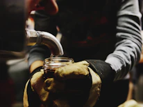 Hands gently pouring golden desi ghee into a traditional brass container.