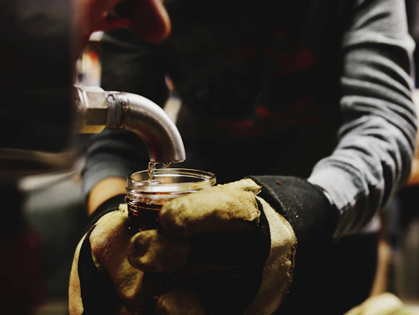 Hands gently pouring golden mustard oil into a glass jar, emphasizing purity and care.