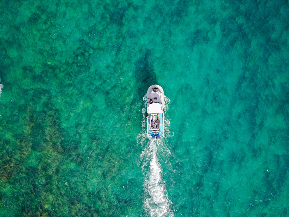 昼間の水域を航行する白いボートの航空写真