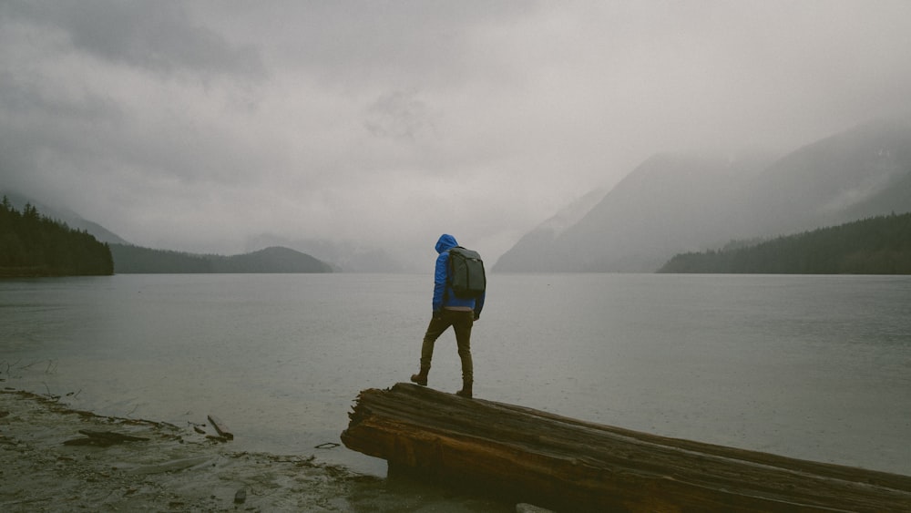 Homme debout sur une plate-forme en bois devant l’eau pendant la journée