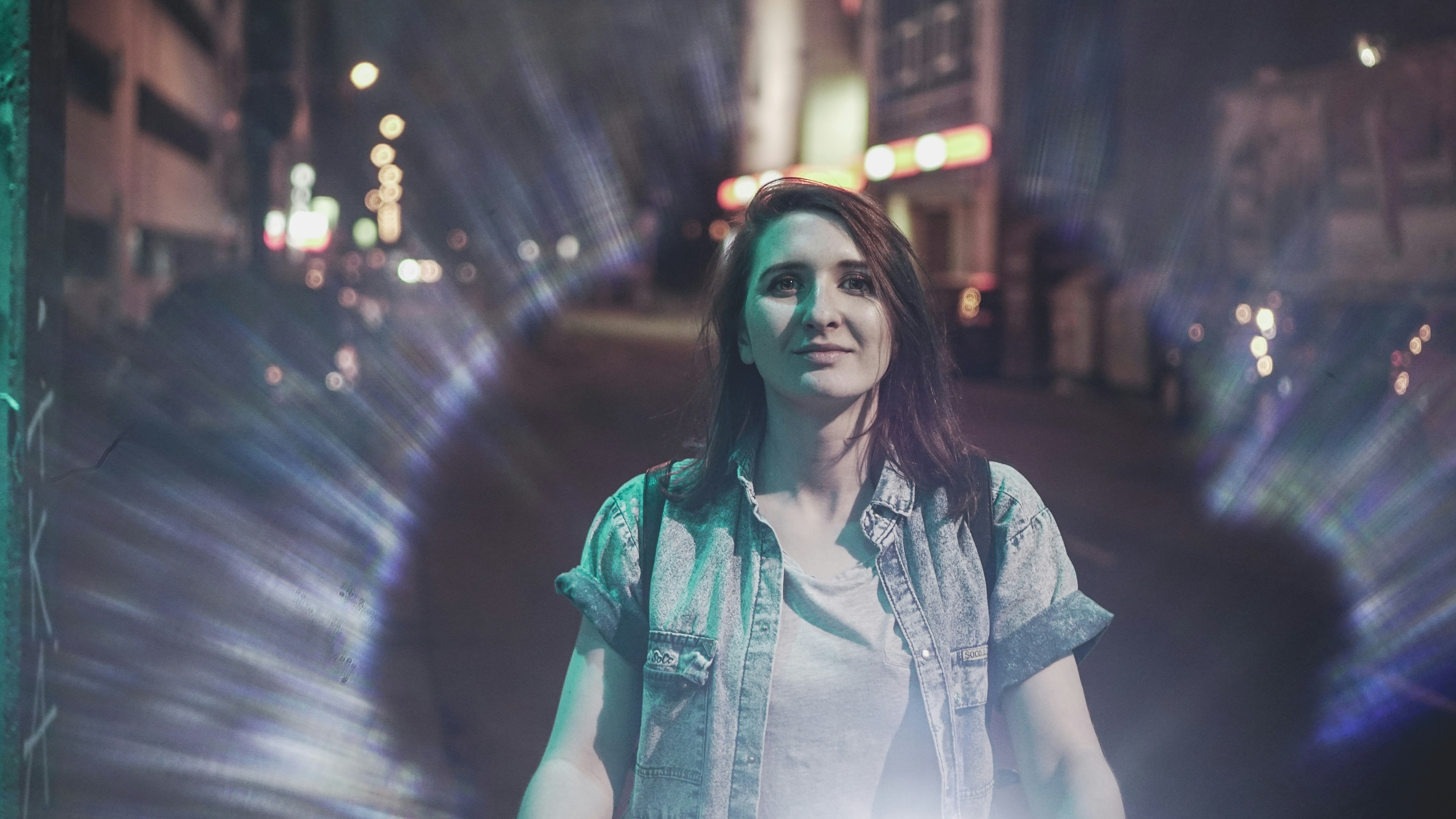 woman in blue denim button up shirt standing on road during night time