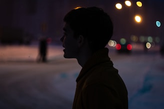 Elegant silhouette of a confident woman against a soft-lit urban backdrop at night.