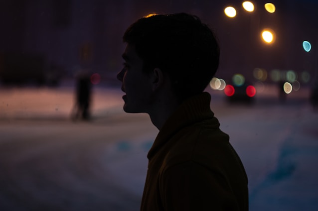 Elegant silhouette of a confident woman against a soft-lit urban backdrop at night.